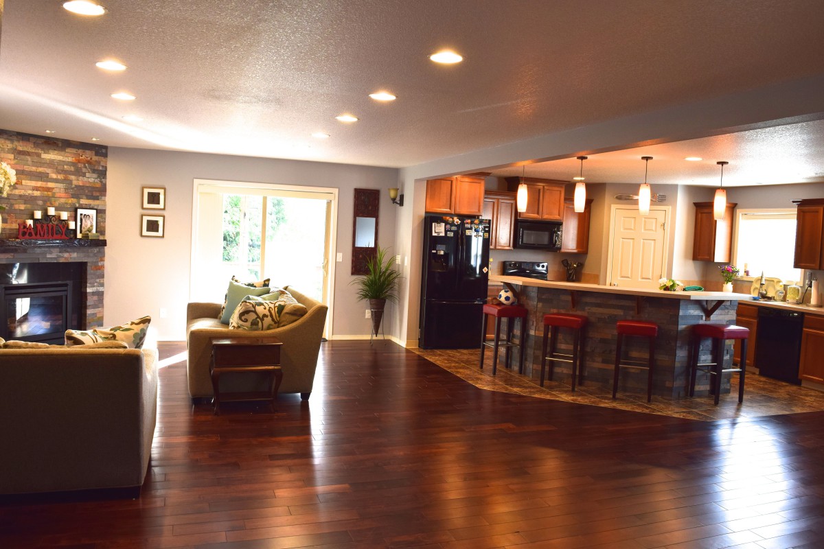 A modern open floor plan featuring a spacious living room and kitchen with hardwood flooring.