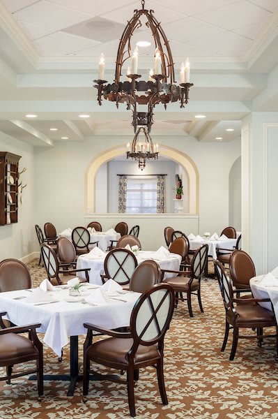 An elegant dining room with neatly set tables and a classic chandelier.