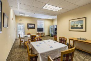 A dining area with a table, chairs, vending machines, and artwork on the walls.