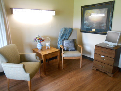 A cozy corner featuring two chairs, a wooden table, and a dresser, creating a warm living space.