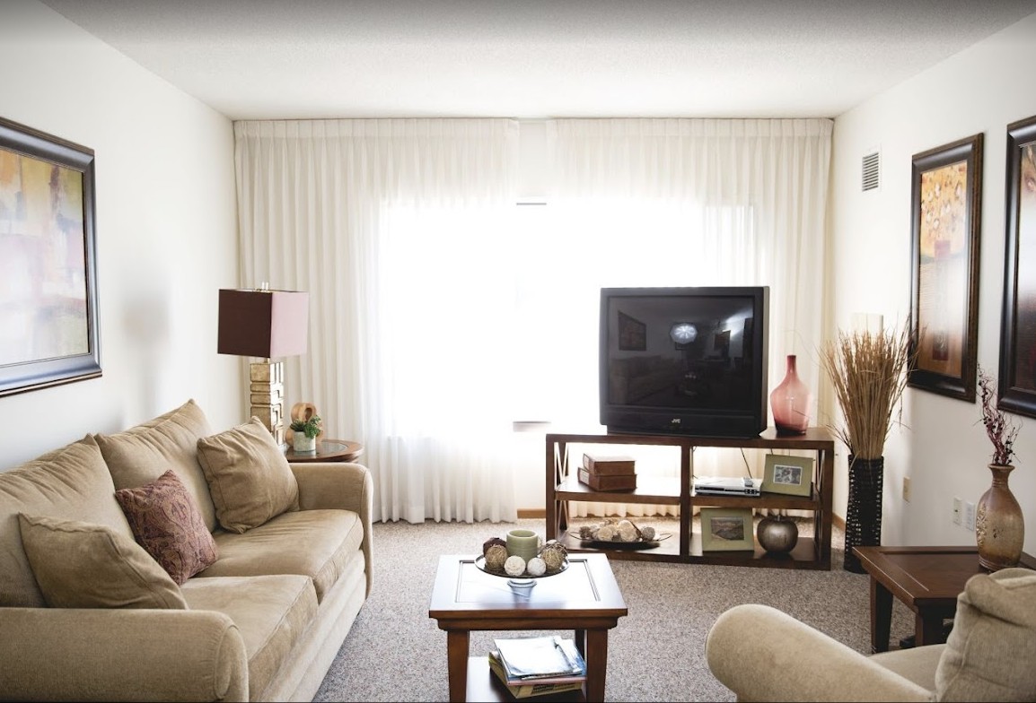 A cozy living room with a sofa, coffee table, and television, featuring neutral tones and elegant decor.