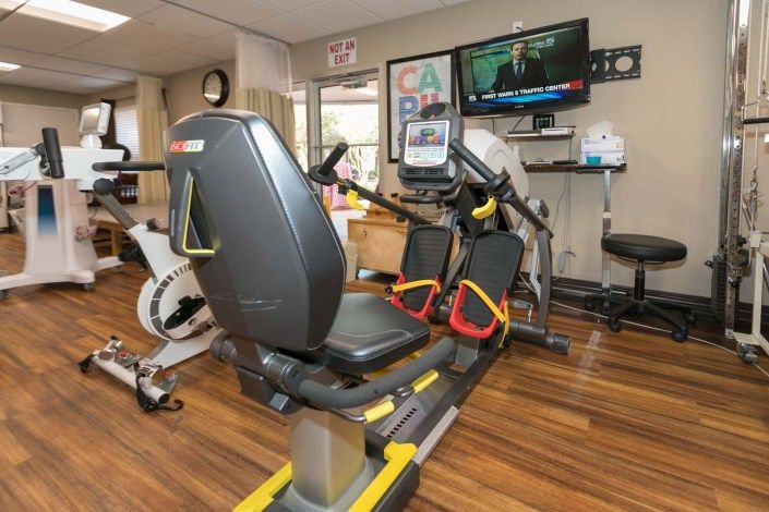A gym with a recumbent exercise bike and a television mounted on the wall.