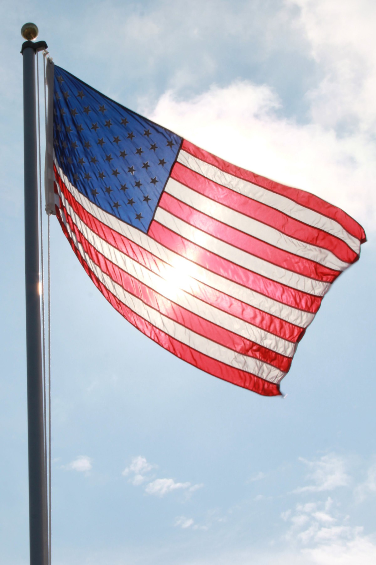 An American flag waving against a bright sky.