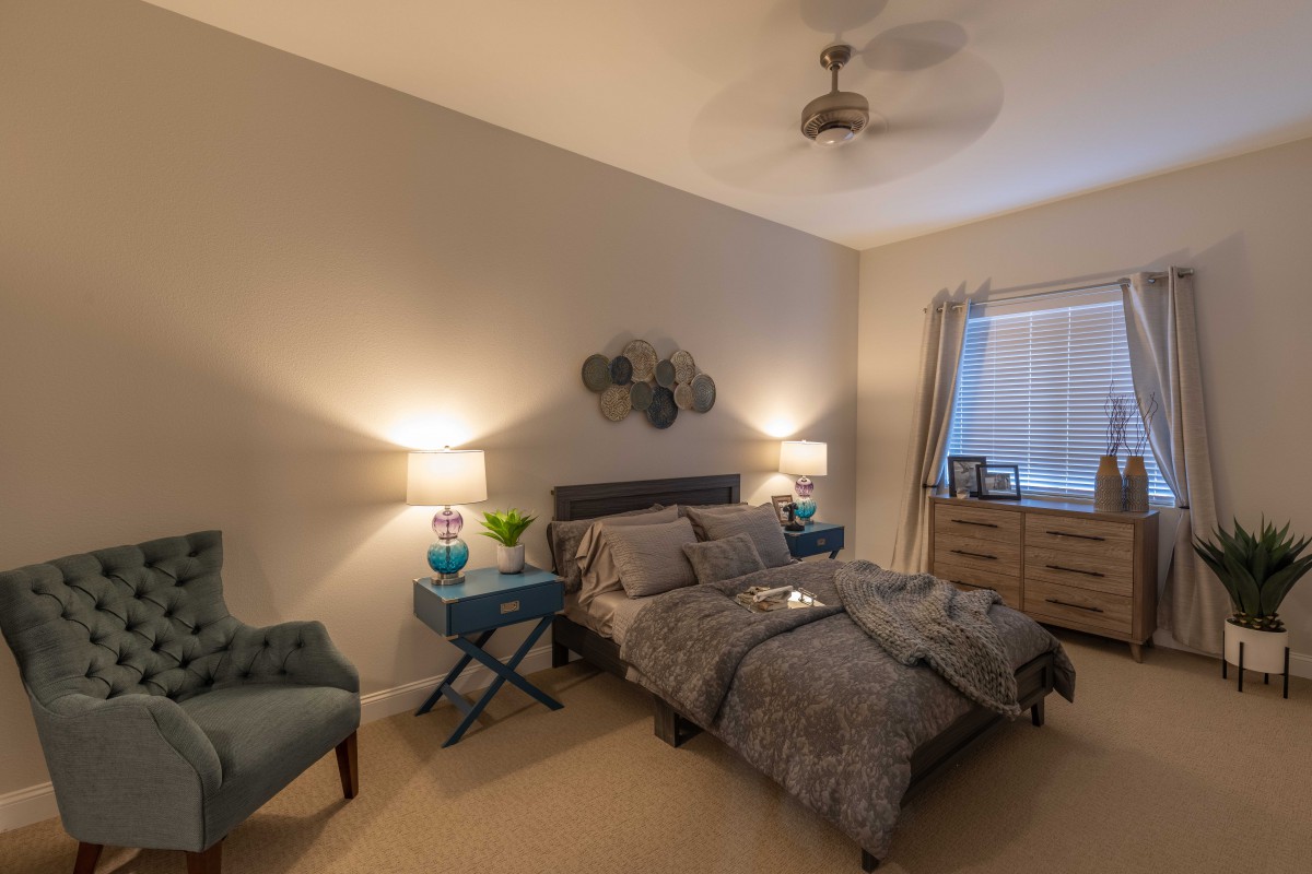 A cozy bedroom with a double bed, lamps on nightstands, and a comfortable chair.