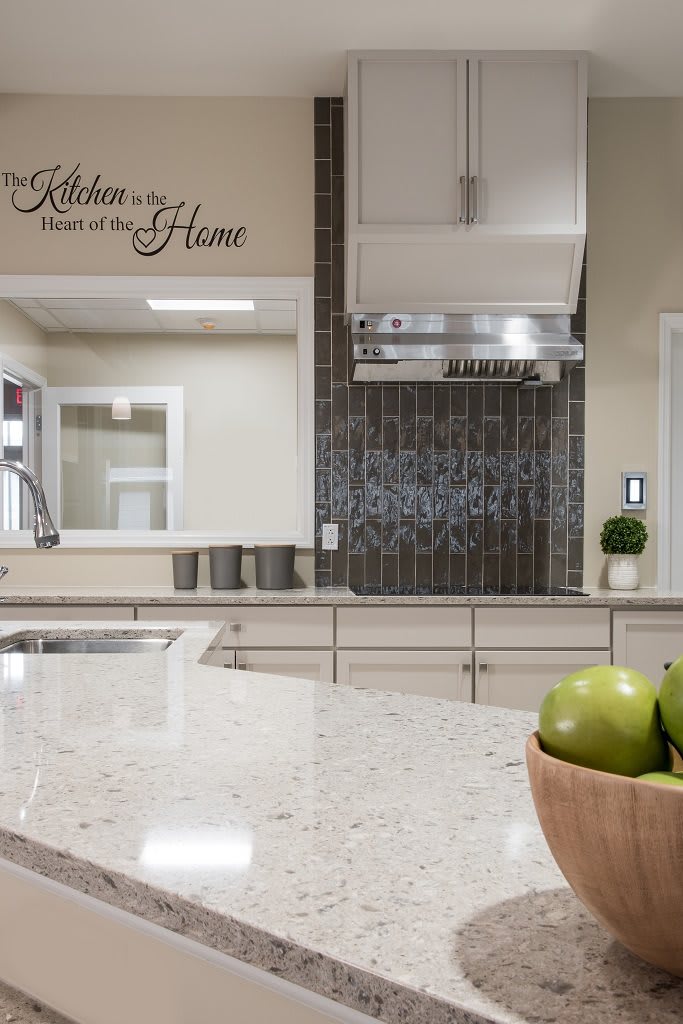 Modern kitchen with a sleek countertop and a wall quote about the heart of the home.
