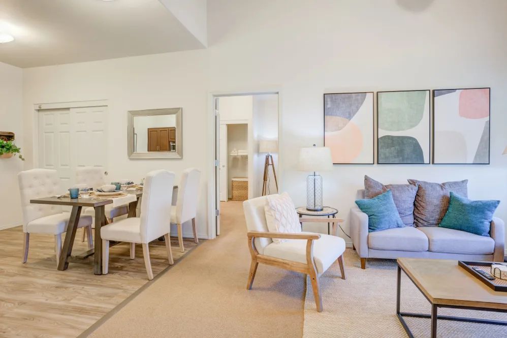A modern living room with a dining area, featuring neutral colors and stylish decor.