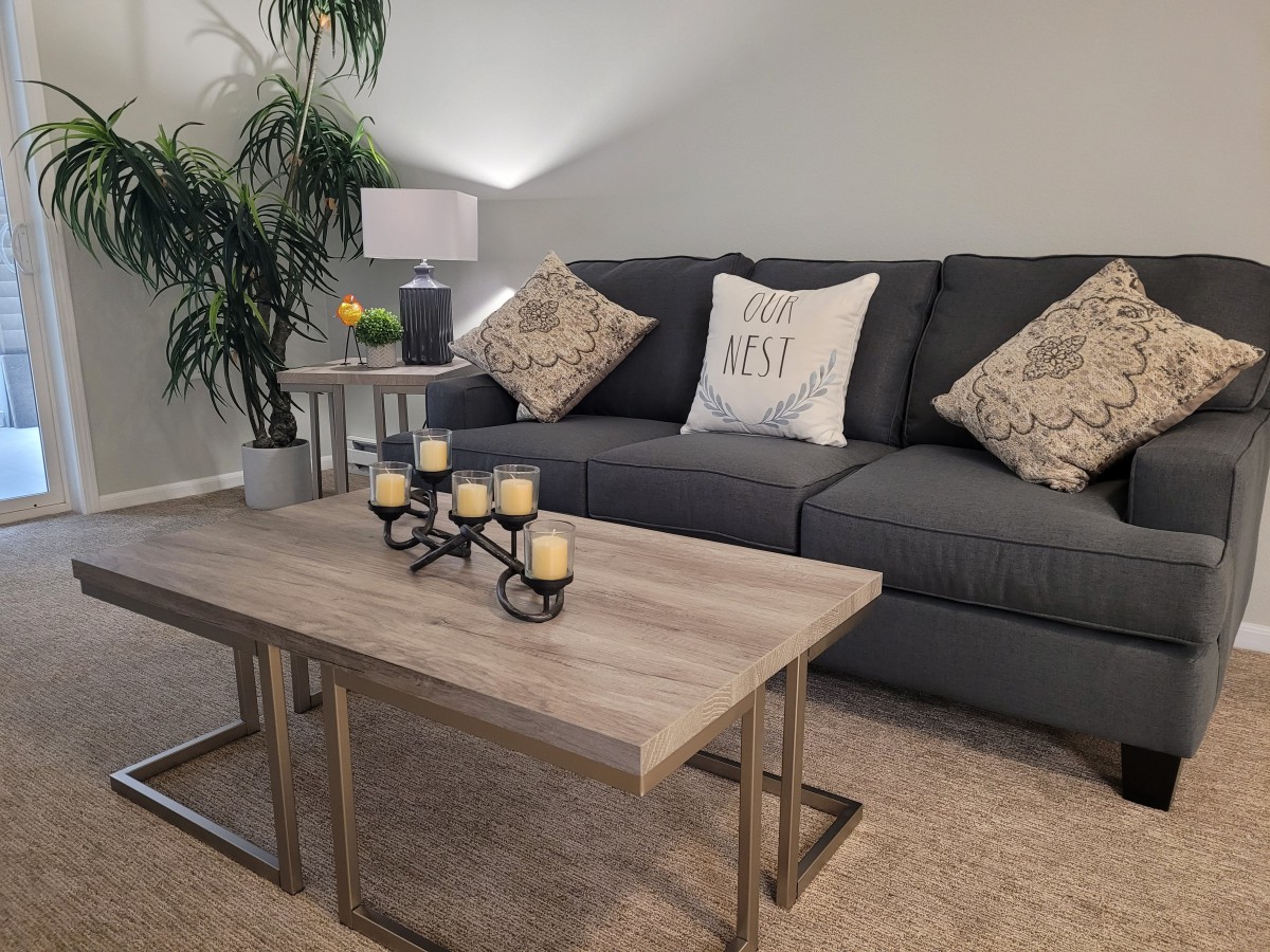 A cozy living room with a dark grey sofa, decorative pillows, and a modern coffee table adorned with candles.