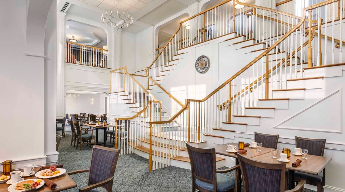 An elegant dining area with a grand staircase and modern decor.