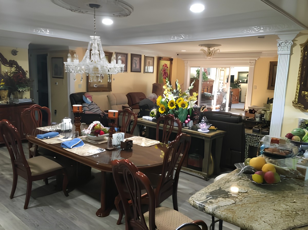 A cozy and well-decorated dining and living room with a chandelier, table settings, and sunflowers adding a warm touch.