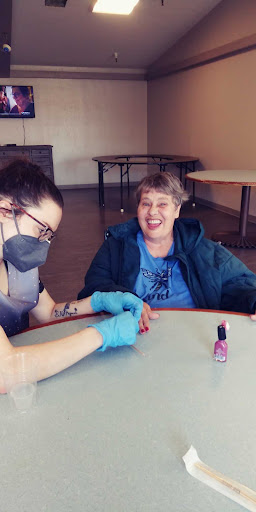 A caregiver applying nail polish during a fun activity with a smiling individual.