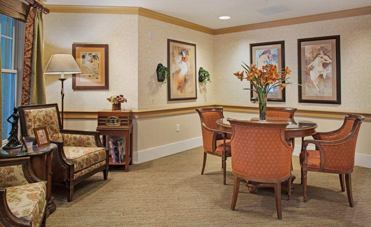 A cozy living room with comfortable seating, decorative artwork on the walls, and a vase of flowers on the table.