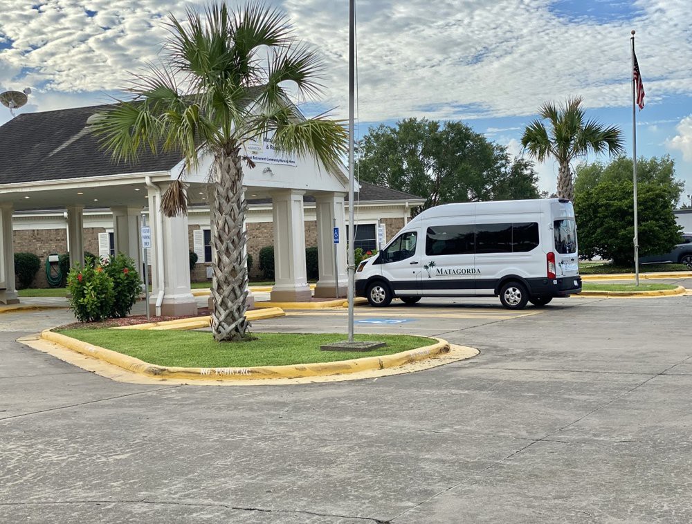 A white van parked outside a building with palm trees and a cloudy sky.