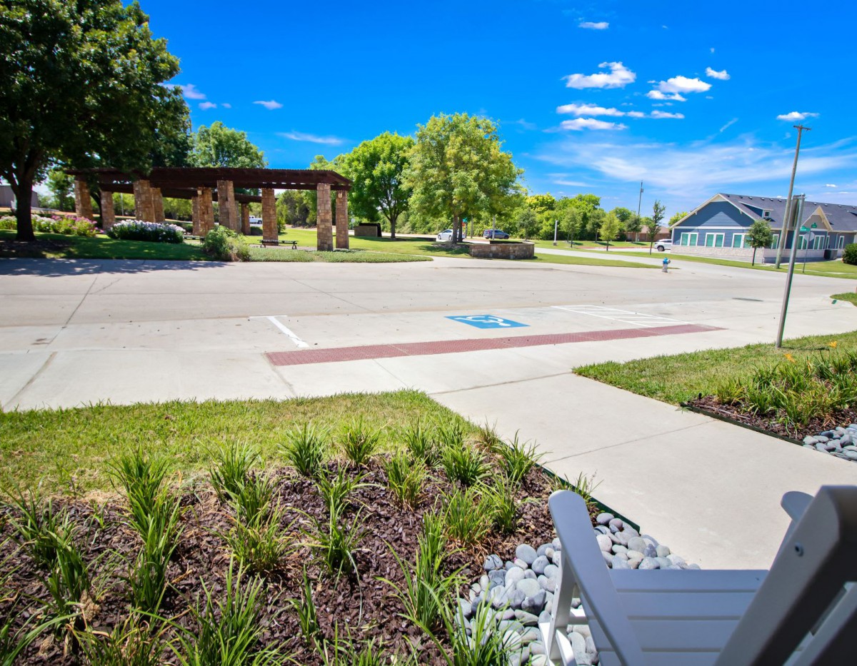 A well-maintained parking area with landscaping and a pavilion under a clear blue sky.