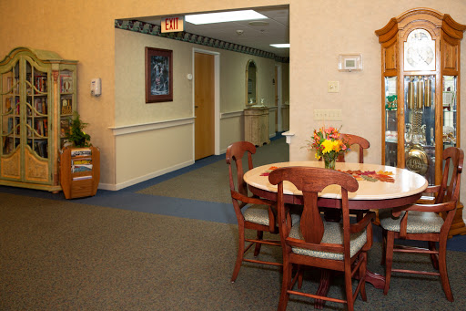 A welcoming dining area with a table and chairs, adorned with flowers, leading to a hallway.