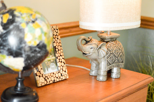A whimsical elephant-shaped lamp beside a decorative frame and a colorful globe.