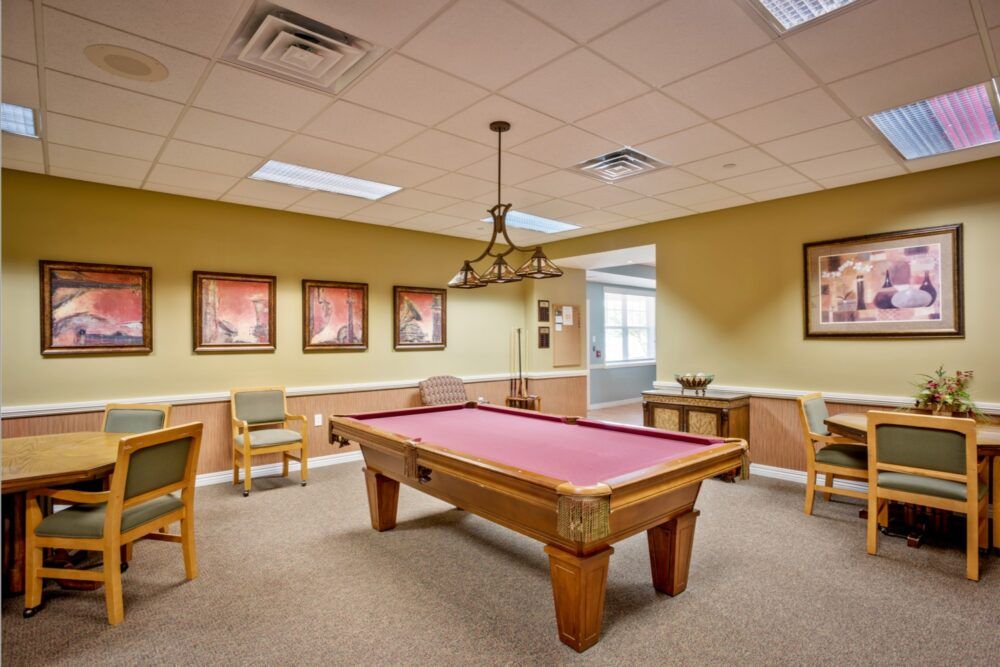 A recreation room featuring a pool table, chairs, and decorative artwork on the walls.