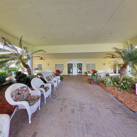 A covered entrance with outdoor seating and lush plants.