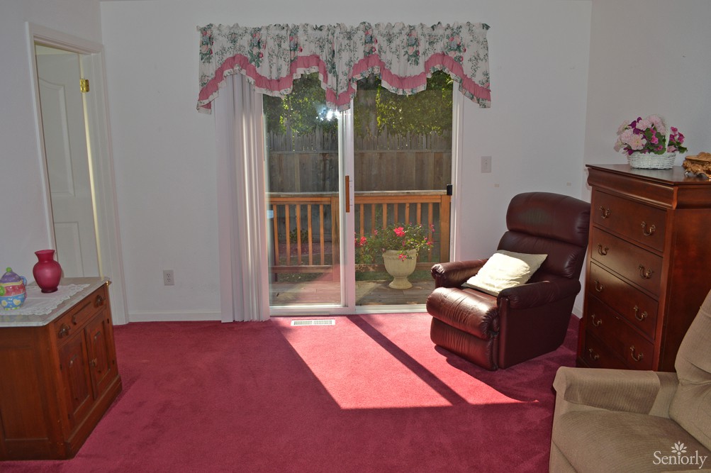 A comfortable living room with an armchair and sliding glass doors leading to a deck.
