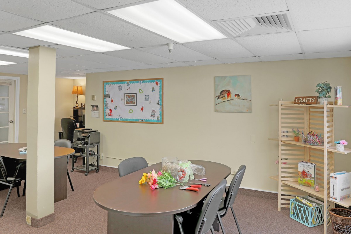 A simple meeting room with a large table, surrounded by chairs and decorated with wall art.