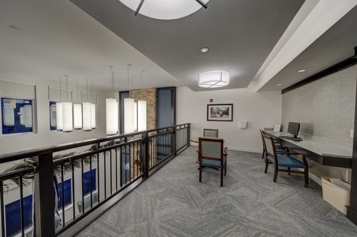 A modern interior space featuring a seating area with desks, carpet flooring, and contemporary lighting.