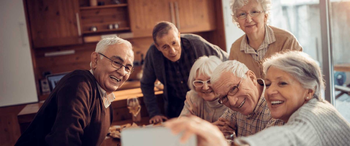 A group of seniors smiling and enjoying time together indoors.