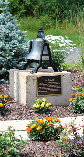 A memorial bell surrounded by a colorful garden.