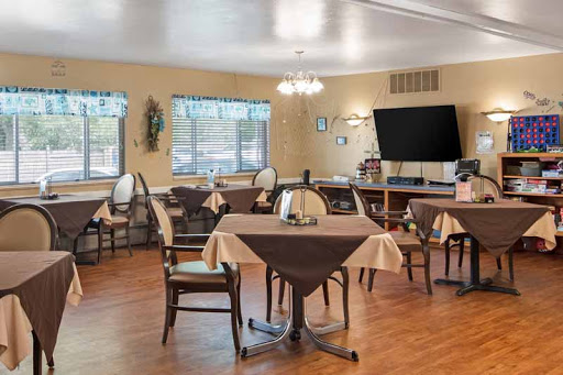 A cozy dining room setup with tables and chairs, featuring a television and ample natural light.