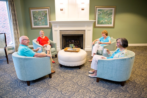 A group of four people enjoying a lively conversation in a cozy lounge with comfortable seating.