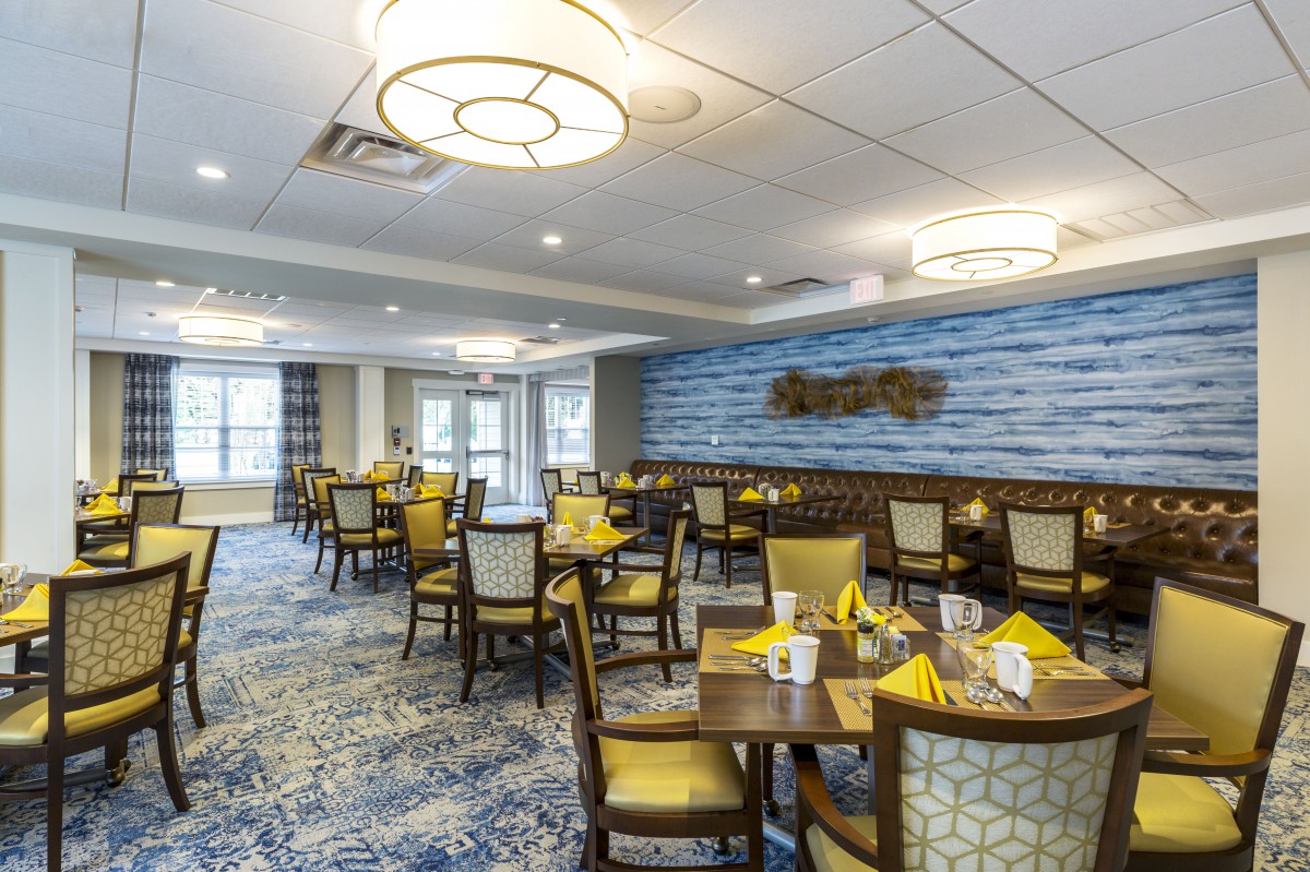 A well-decorated dining area with neatly arranged tables and chairs, featuring elegant lighting and stylish decor.