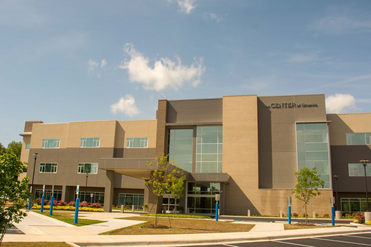 A modern educational building with large windows and a clear sky.