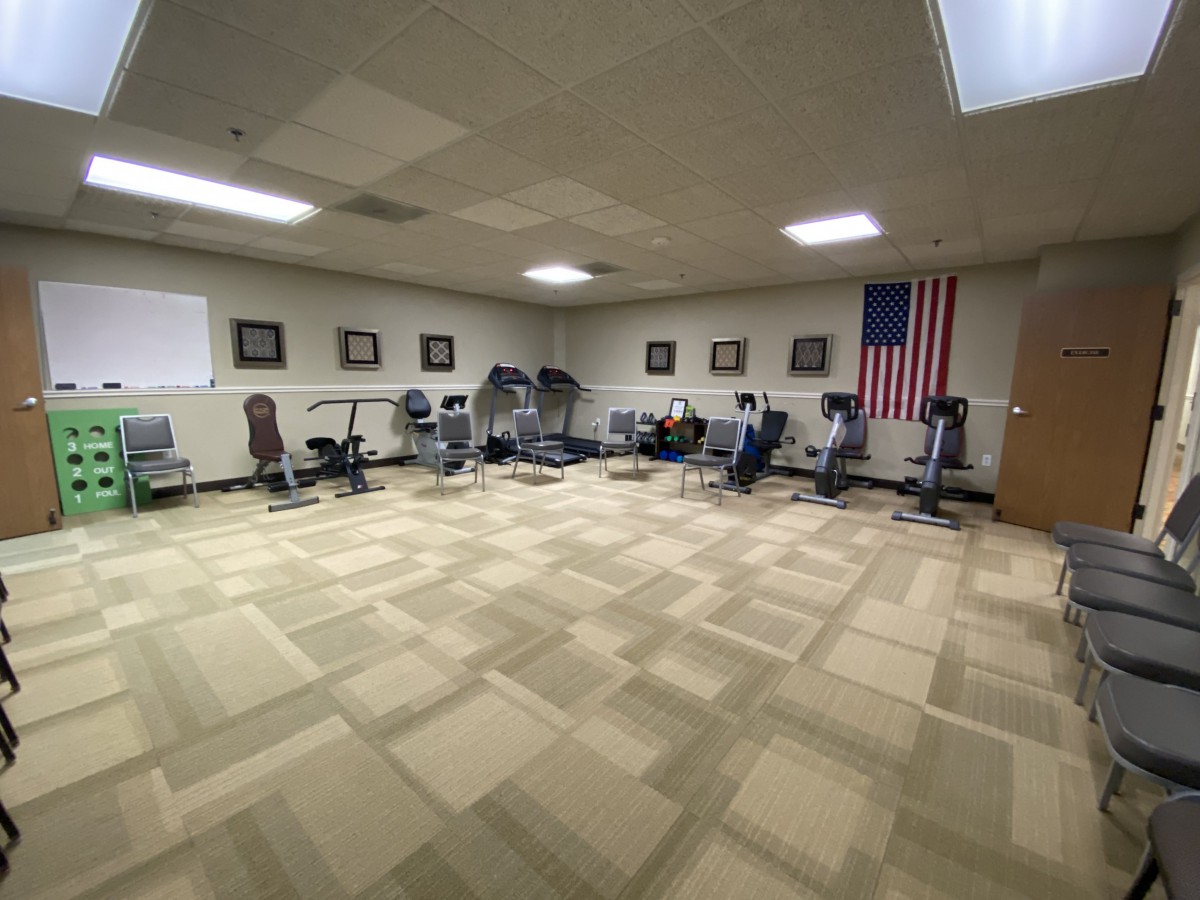 An indoor gym room with exercise bikes lined up under a wall-mounted flag.