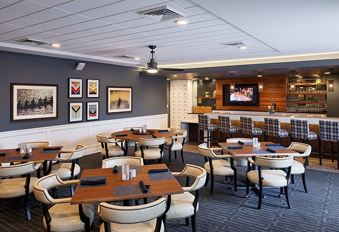 A modern restaurant interior with neatly arranged tables and chairs, featuring a stylish bar area.