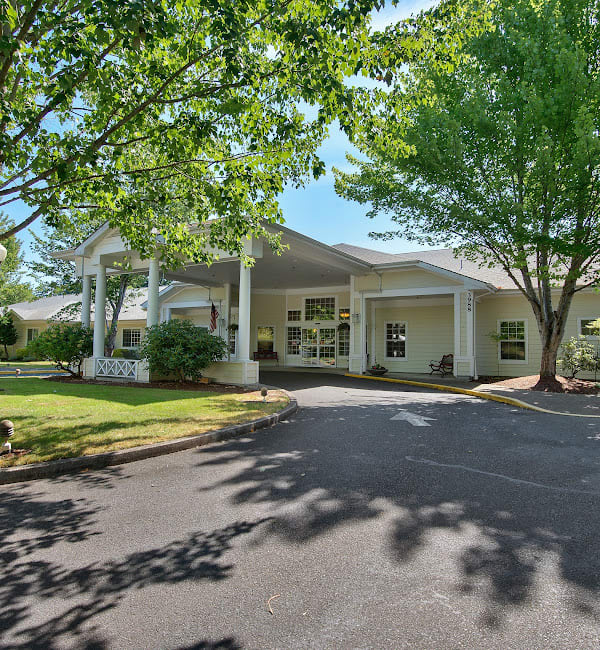 A well-lit building entrance surrounded by lush trees and landscaping.