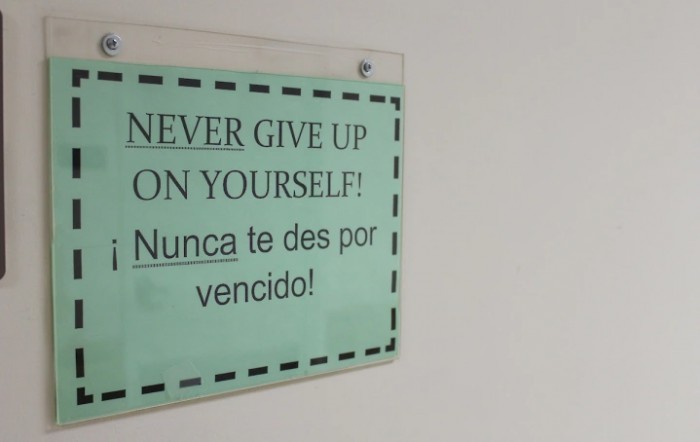 A bilingual motivational sign encouraging perseverance, with text in English and Spanish.