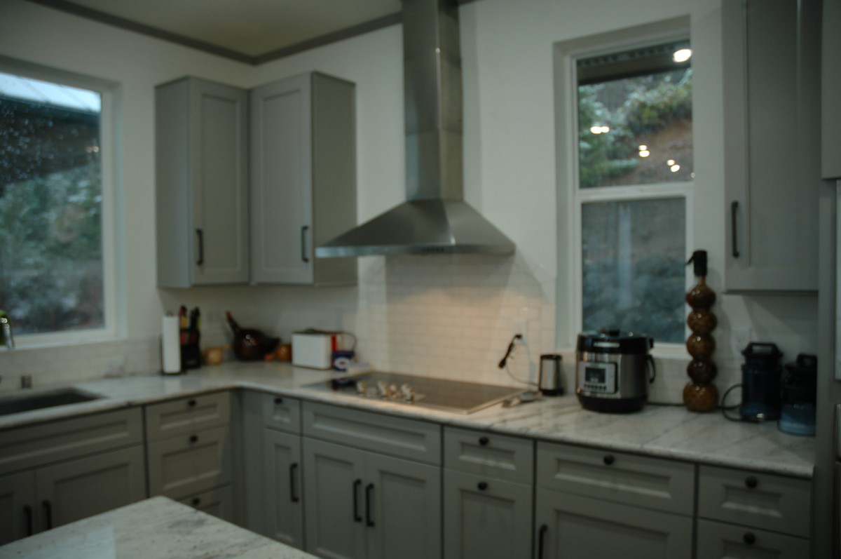 A modern kitchen featuring sleek cabinets and a stainless steel stove hood.