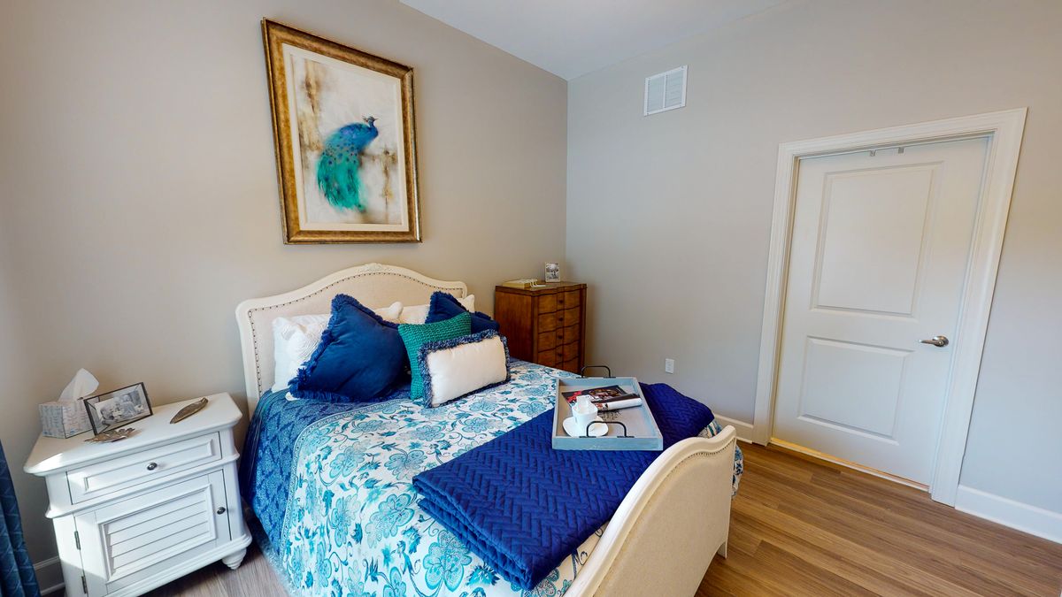 A cozy bedroom featuring a decorative bed with blue and teal bedding, complemented by artwork above the headboard.