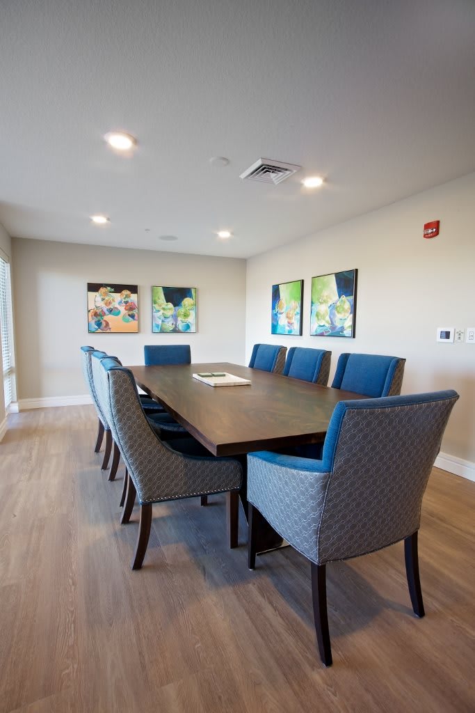 A modern meeting room with a long conference table and upholstered chairs.
