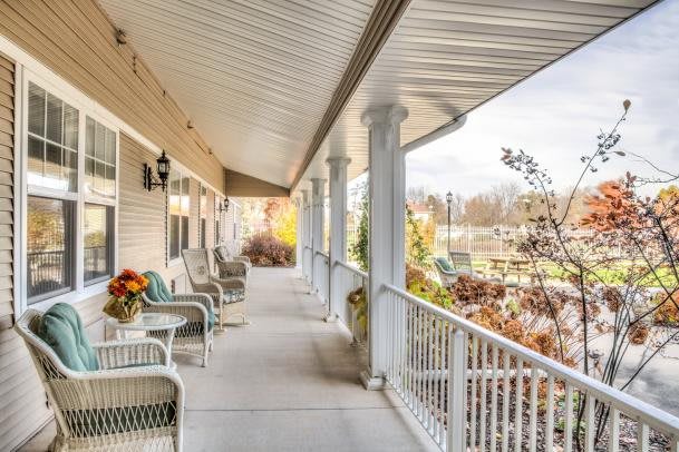 A cozy covered porch with seating, overlooking a serene autumn landscape.