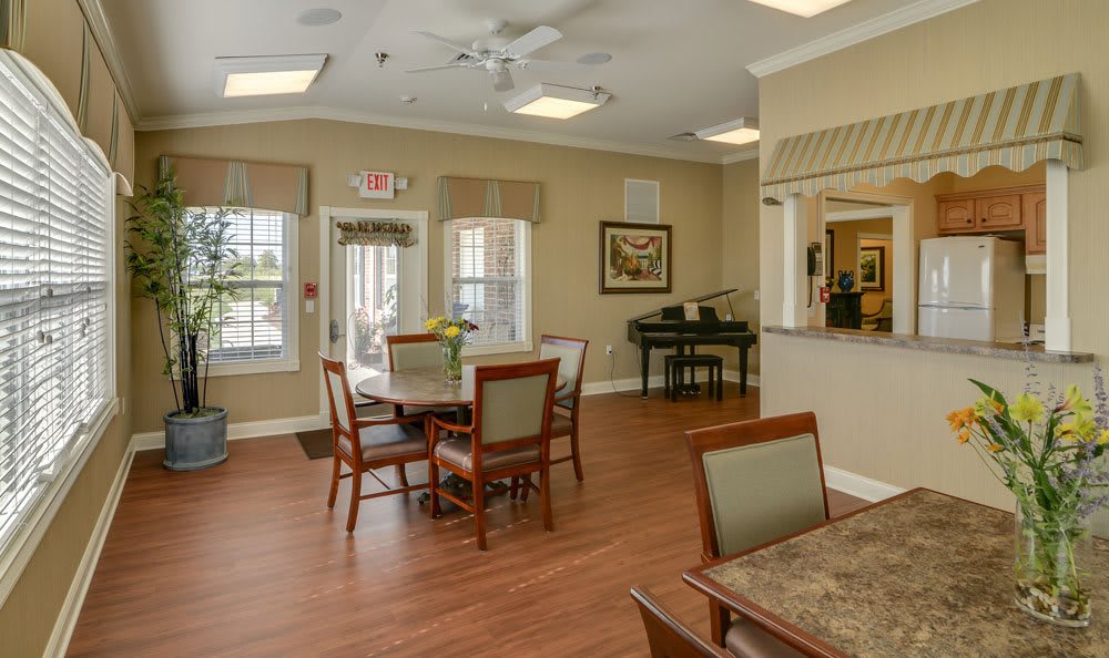 A cozy dining area featuring a piano and several tables with chairs.