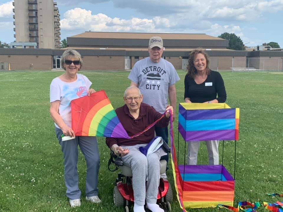 A group of four people enjoying a sunny day in the park with colorful kites.