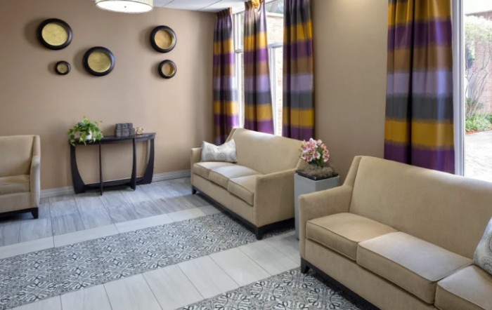 A modern living room with beige sofas, colorful striped curtains, and decorative wall art.