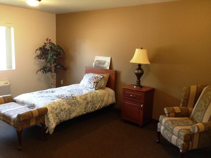 A cozy bedroom with a single bed, nightstand, and lamp.