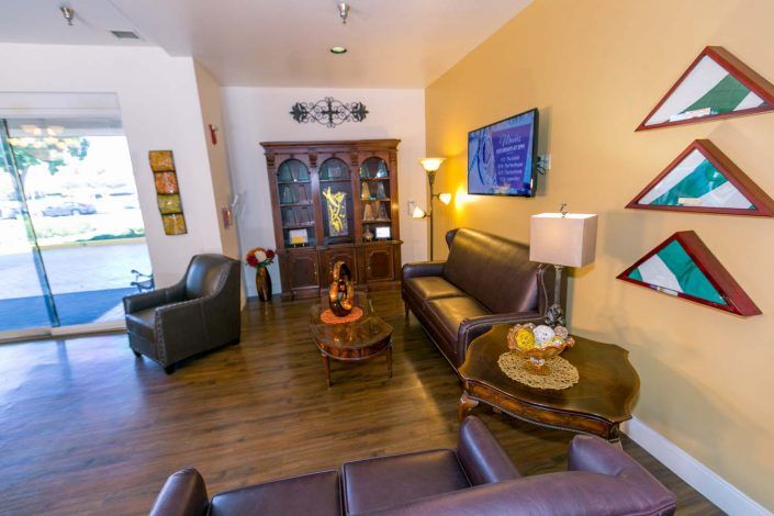 A cozy living room with leather sofas, wooden flooring, and decorative elements including a tall cabinet and wall art.