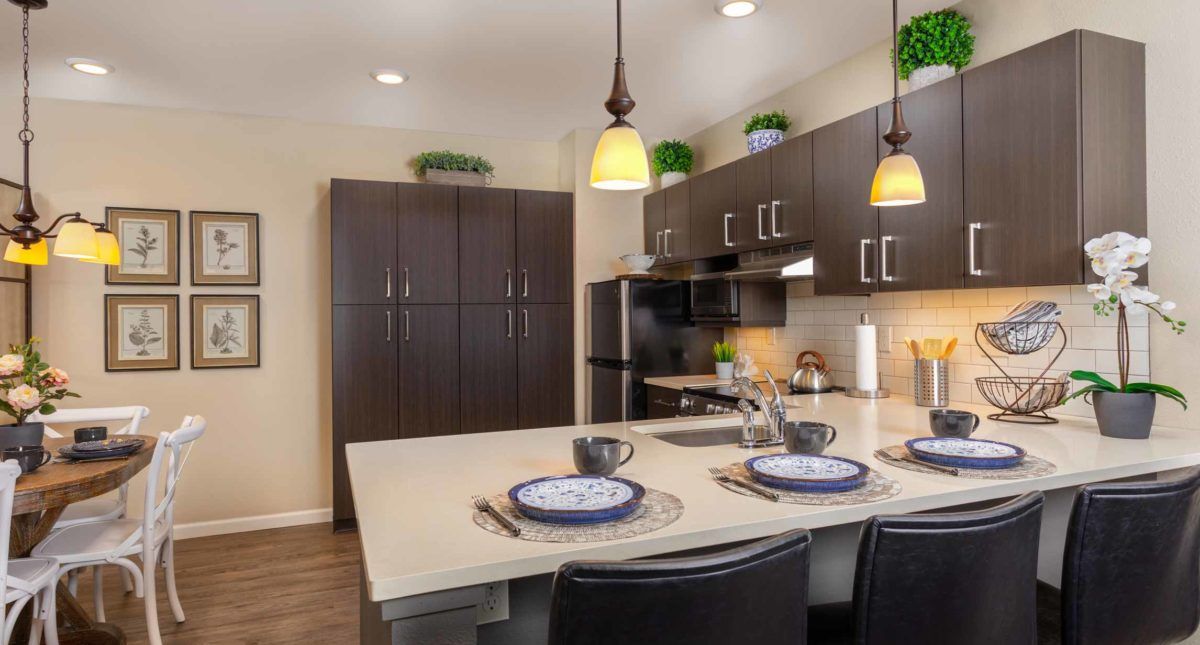 A modern kitchen interior featuring a stylish countertop with place settings and pendant lighting.