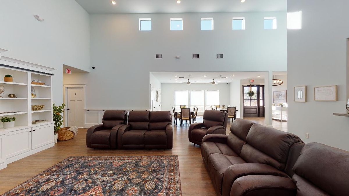 Spacious living room with leather seating and a view into the dining area.