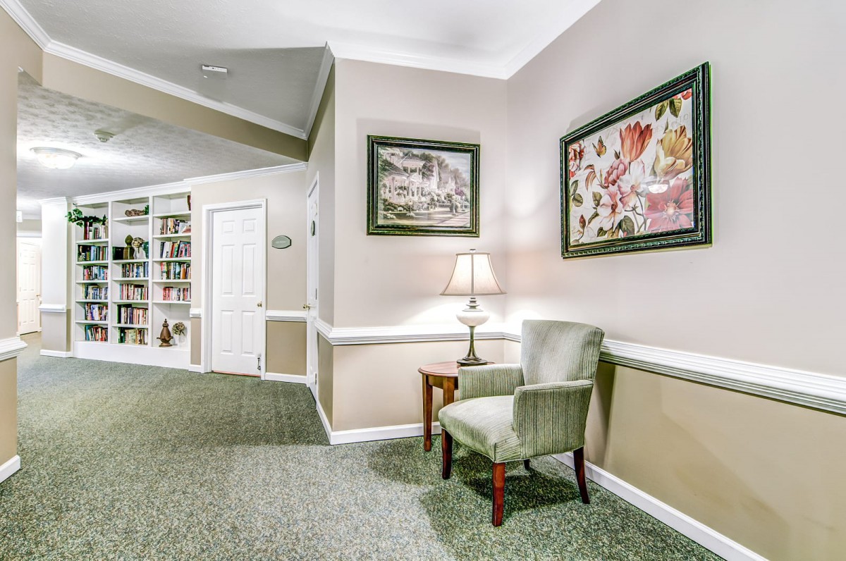 A cozy hallway with a chair, side table, and decorative paintings on the wall.