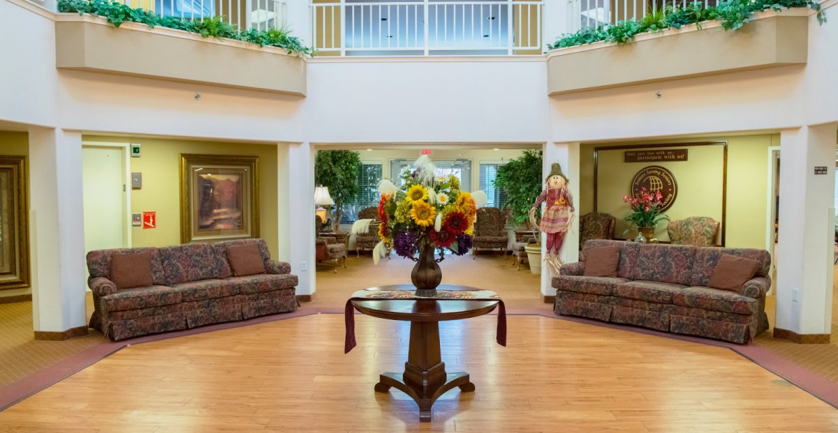 A welcoming lobby area featuring a central table with a floral arrangement, surrounded by comfortable seating.