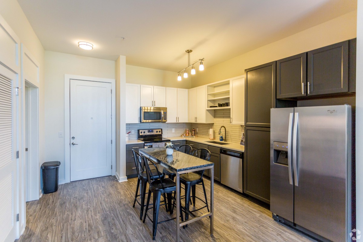 A modern apartment kitchen featuring stainless steel appliances and a central island with seating.