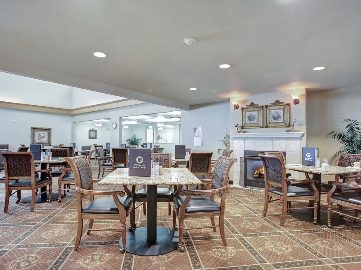 A cozy dining area with multiple tables and chairs, featuring a fireplace and elegant decor.