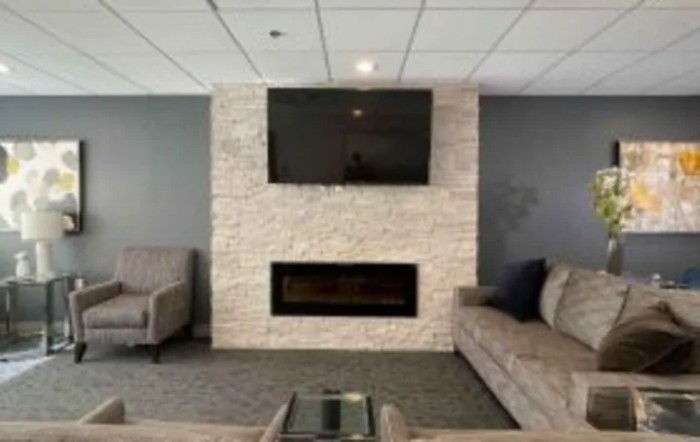 A modern living room featuring a mounted television above a stone fireplace, flanked by comfortable sofas.
